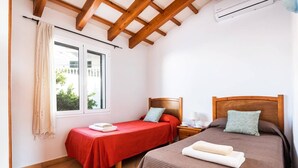 Un dormitorio con dos camas, una ventana y un ventilador de techo.