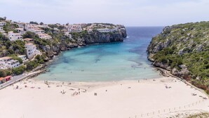 Un pueblo costero con playa, edificios y acantilados rocosos.