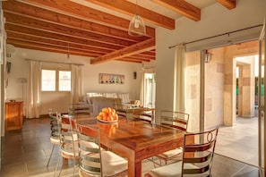 Un coin repas avec une table et des chaises en bois, un tableau accroché au mur et une vue à travers une porte vitrée.