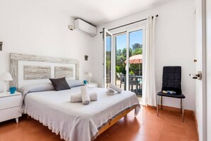 Un dormitorio con cama, una silla, una mesa y vistas al exterior.