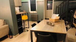 Une cuisine moderne avec un coin repas, comprenant une table en bois, des chaises noires et un lampadaire jaune.