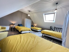 Una habitación con dos camas, una silla, una lámpara y una ventana.