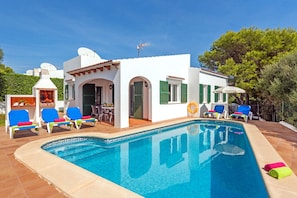 A poolside area with a pool, lounge chairs, and a barbecue area.