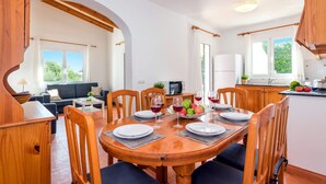 A dining area with a wooden table set for four, surrounded by wooden chairs. - Villa Sirenita by Villa Plus (Los Delfines)