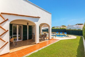 A modern house with a swimming pool, outdoor seating, and a well-maintained lawn.