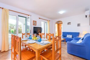 A dining area with a wooden table set for four, a television, and a blue sofa.