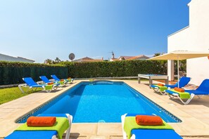 A swimming pool with lounge chairs and a sun umbrella.