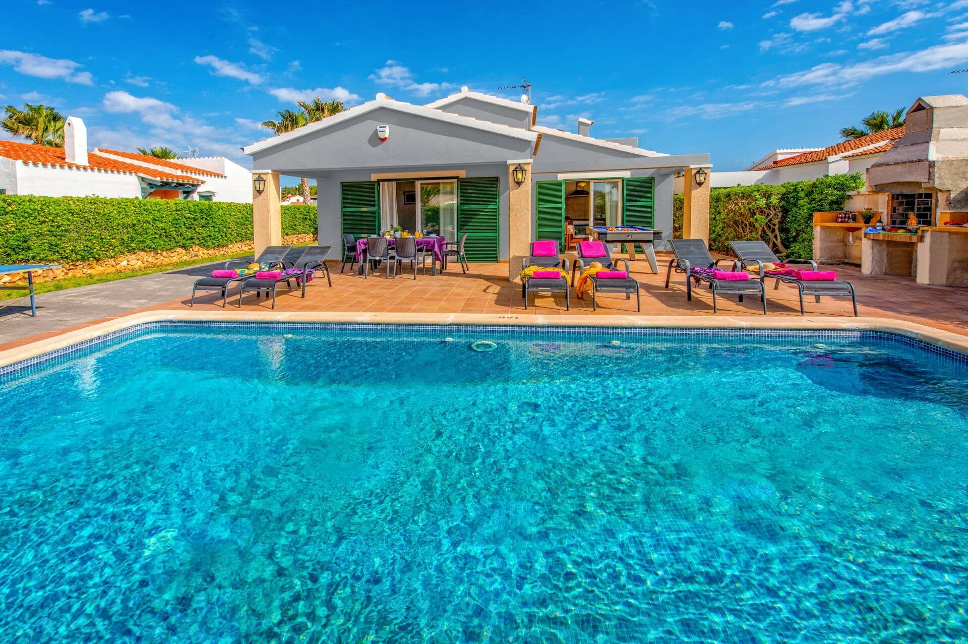 A swimming pool with lounge chairs and a covered seating area.