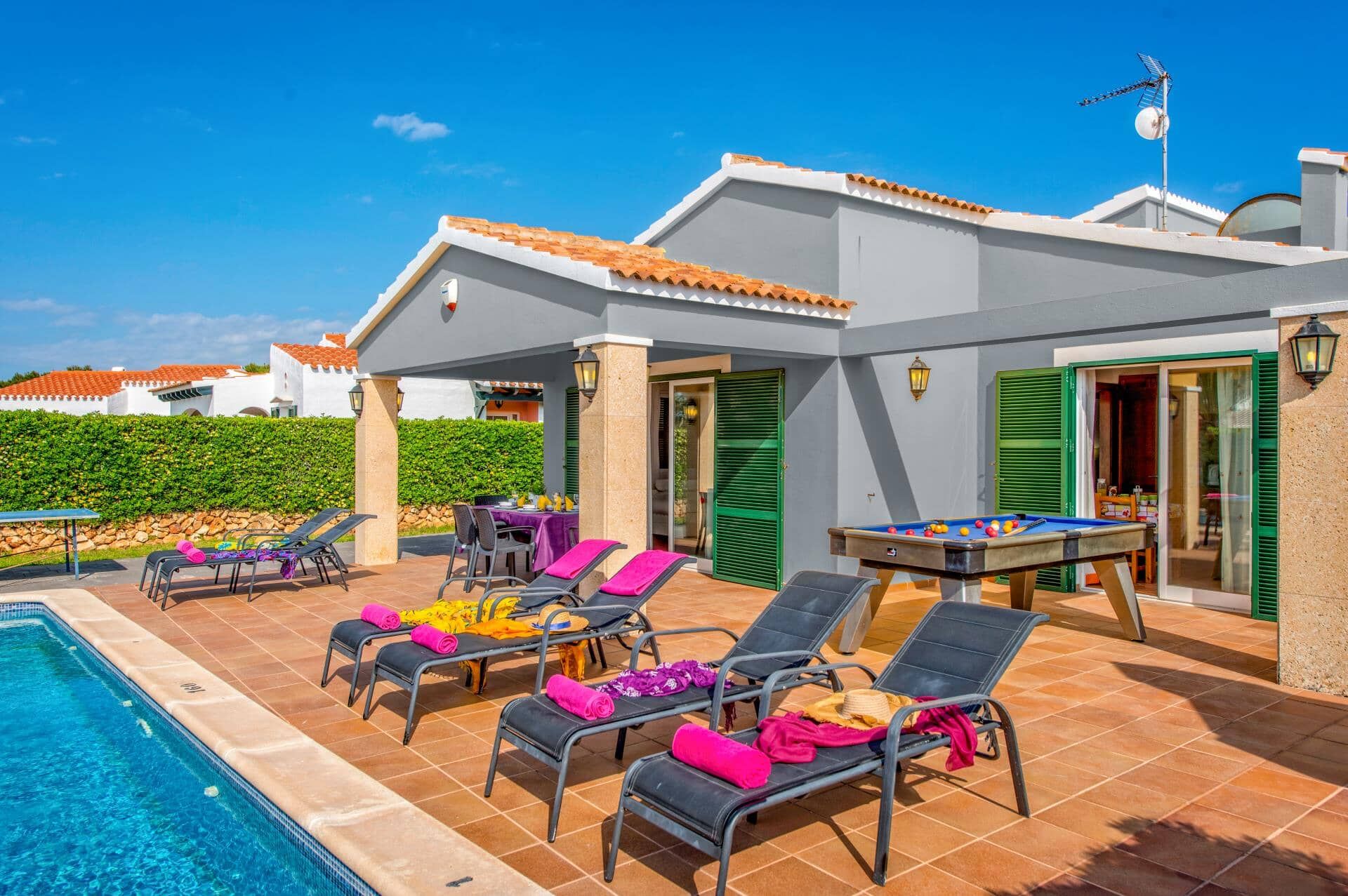Un espace aménagé au bord de la piscine, avec des chaises longues, une piscine et une table de billard.