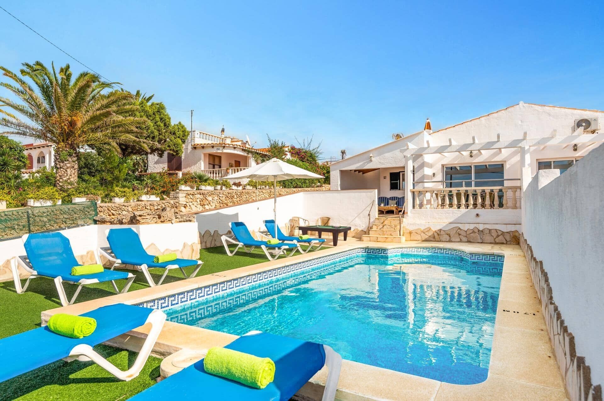 A pool area with blue lounge chairs and a small pool.