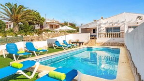 Un espace piscine avec des chaises longues bleues et une petite piscine.
