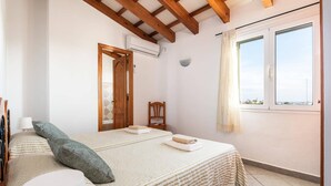 Ein Schlafzimmer mit Bett, Stuhl, Fenster und Tür.