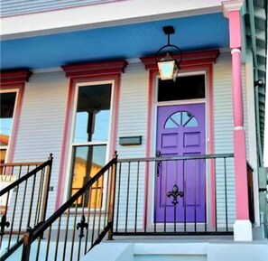 A house with a purple door, a blue and pink exterior, and a black railing on the porch. - Stylish Stay Haven 6 (New Orleans)