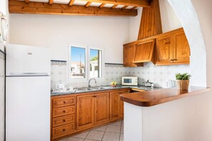 A kitchen with wooden cabinets, a white refrigerator, a microwave, and a sink.
