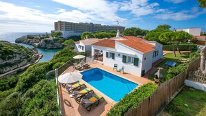Eine Villa mit Swimmingpool, umgeben von üppiger Vegetation mit Blick auf die Küste.