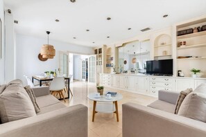 A modern living room with a sofa set, a coffee table, and a television on a cabinet.