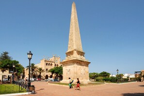 A tall obelisk in a square with a historic building in the background. - Villa Violeta by Villa Plus (Cap d'Artrutx)