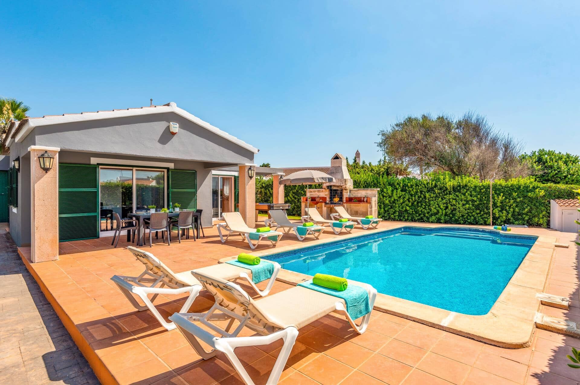 Une piscine avec des chaises longues et un espace barbecue.