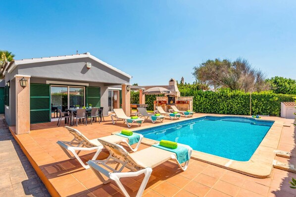 A swimming pool with lounge chairs and a barbecue area.