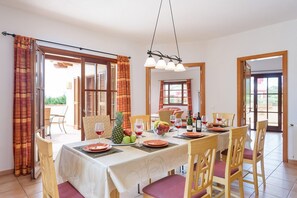 A dining area with a table set for four, chairs, a chandelier, and a view of the outdoors.