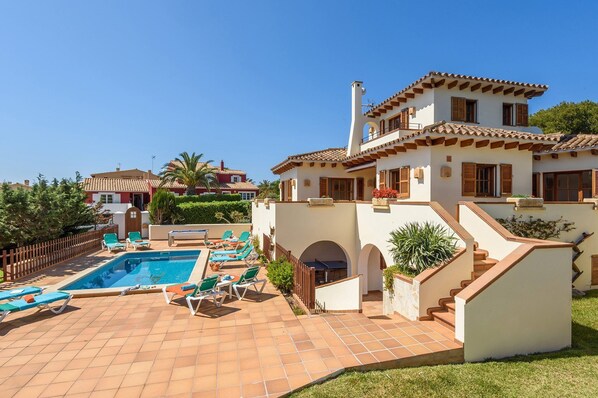 A two-story house with a swimming pool, outdoor seating, and a staircase leading to the upper floor.