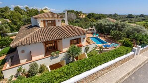 Una villa con piscina, rodeada de exuberante vegetación y vistas despejadas al mar.
