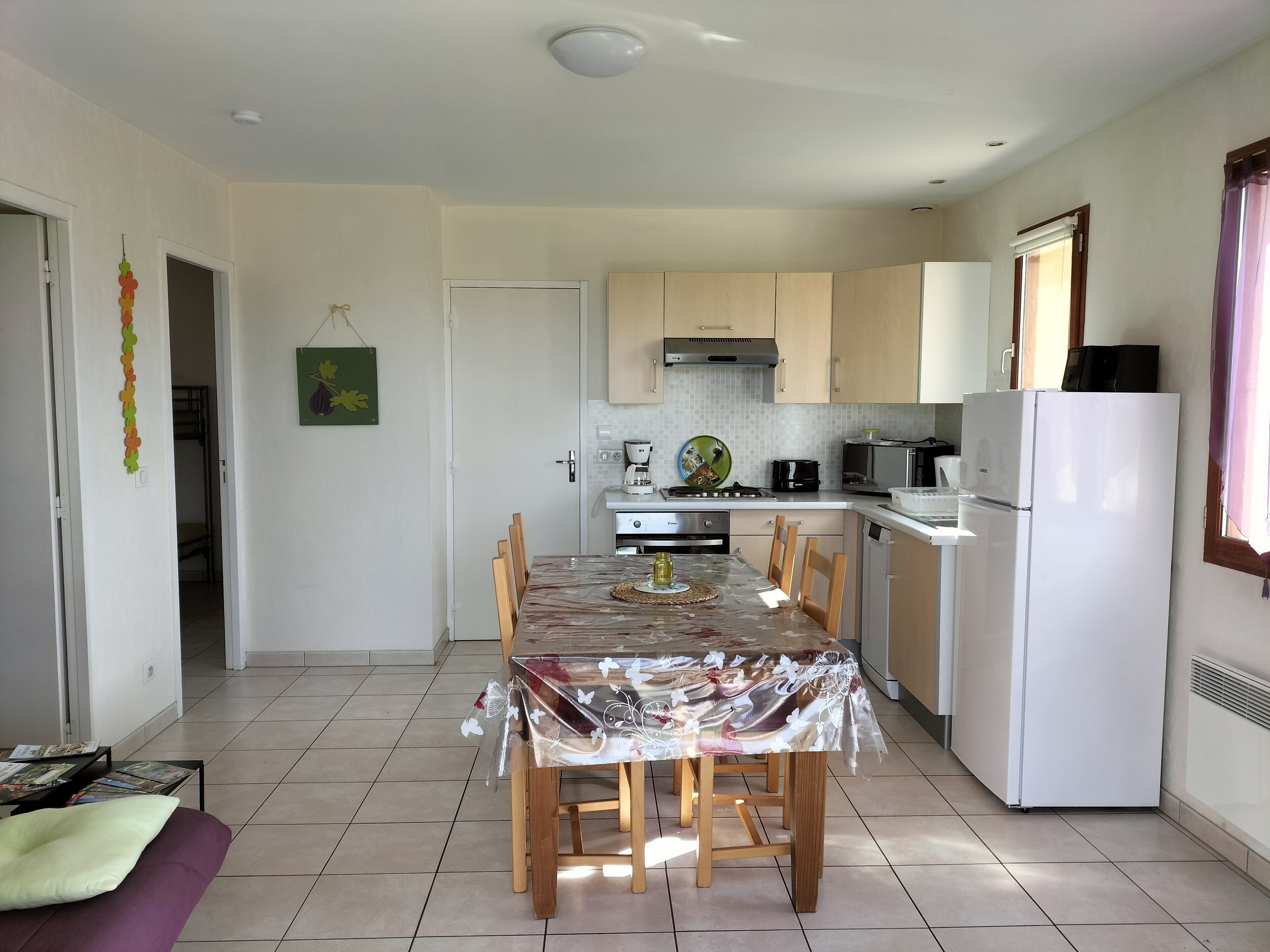 A compact kitchen with a dining table, chairs, a refrigerator, and a microwave.