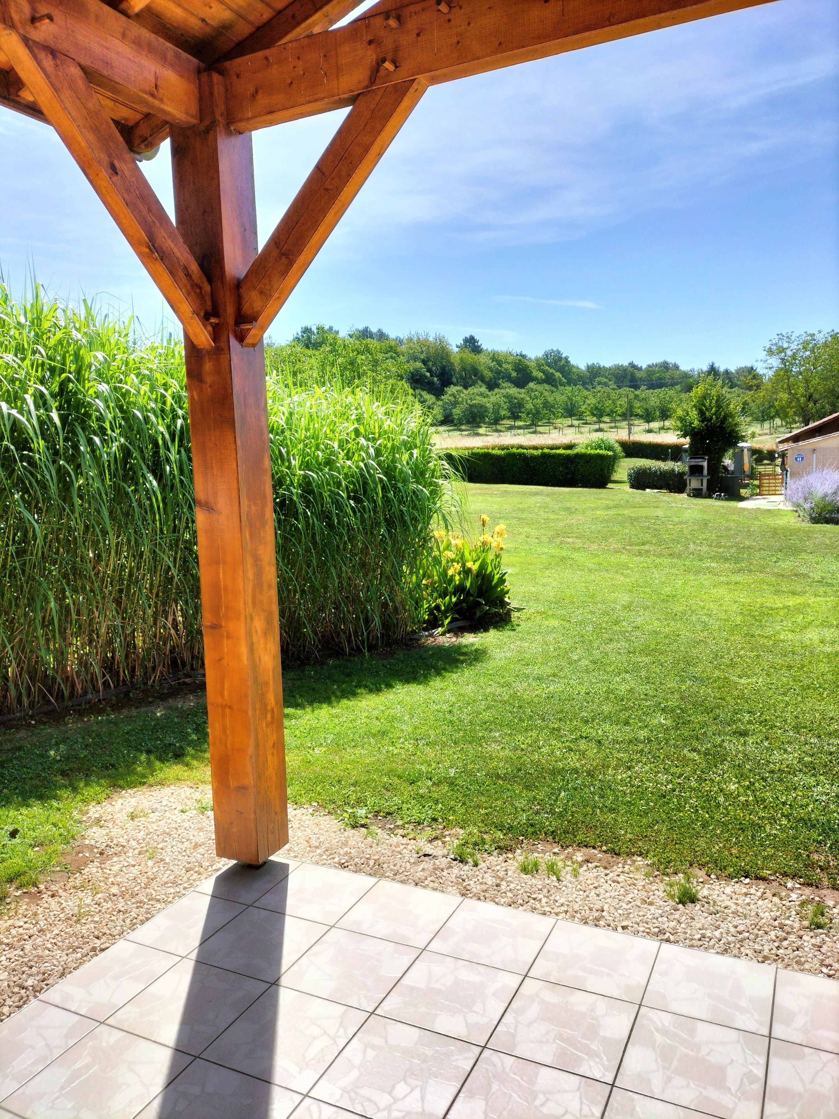 Una pérgola de madera con un patio de baldosas.