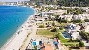 Vista aérea de un pueblo costero con playa, un hotel de varios pisos y vistas al mar.