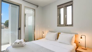 Un dormitorio con cama, mesitas de noche, una ventana y una puerta.