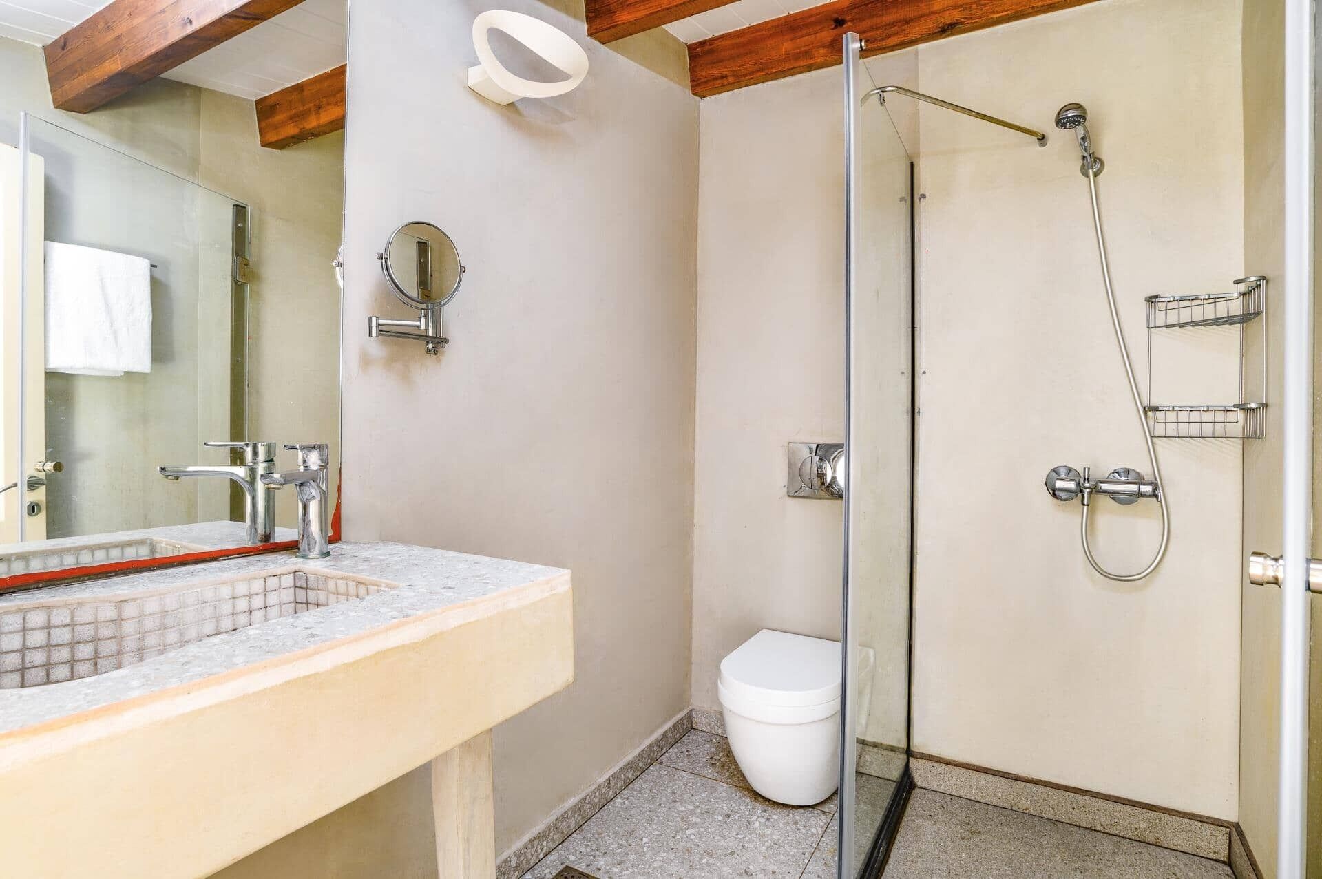 Une salle de bain avec une douche à parois de verre, des toilettes blanches et un lavabo avec un miroir.