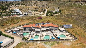 Villa Beatrix Seastone, una amplia villa con varias piscinas y fachada de piedra, rodeada de un paisaje montañoso.
