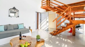 En moderne stue med en trappe i træ, en sofa, et sofabord med frugt og et spejl.