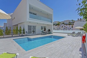 A modern two-story building with a swimming pool, outdoor seating, and a view of the surrounding hillside. - Villa Dona Julia by Villa Plus (Praia do Carvoeiro)