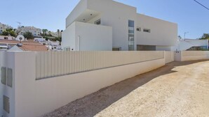Un edifici modern de color blanc amb teulada plana i un balcó gran.
