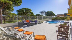 Un espace aménagé au bord de la piscine, avec des chaises longues, une petite table et une piscine.
