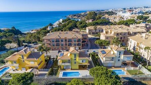Un quartier résidentiel situé sur la côte, composé de plusieurs maisons à deux étages, d’une piscine et offrant une vue sur la mer.