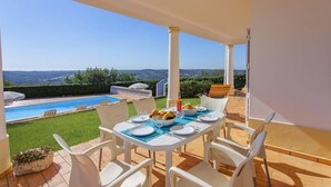 A terrace with a dining table set for two, overlooking a swimming pool and a scenic view. - Villa Colina do Sol by Villa Plus (Paderne)