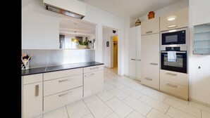 Een moderne keuken met witte kasten, een zwart aanrecht en ingebouwde apparaten, waaronder een magnetron en oven.