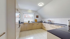 Una cocina moderna con encimera negra, armarios color beige y una ventana con vista a un edificio.