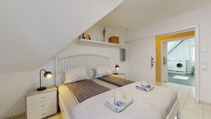 Un dormitorio con una cama, mesitas de noche, una lámpara y vistas al cuarto de lavado.