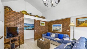 Ein Wohnzimmer mit Backsteinwand, Fernseher, Sofa und Couchtisch.