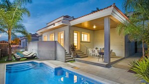 A modern house with a swimming pool, outdoor seating, and a covered patio.