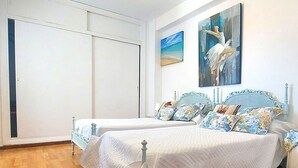 Une chambre avec deux lits, une armoire et un tableau représentant une ballerine.