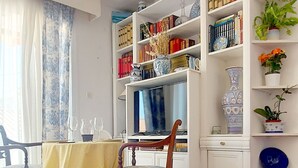 Un coin repas avec une table en bois, des chaises et une bibliothèque remplie de livres et d’objets décoratifs.