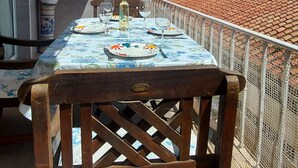 Un balcon avec une table dressée pour le dîner, des plantes en pot et une vue sur le paysage urbain.