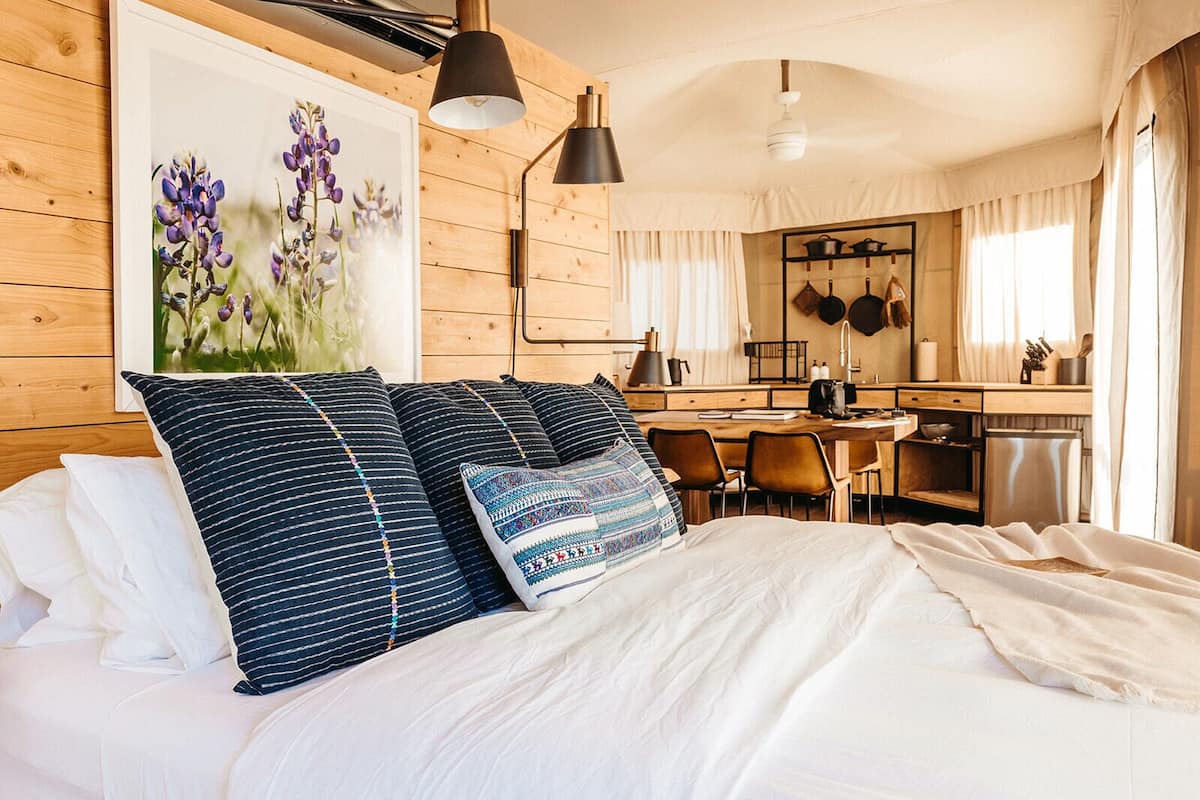 Ein Schlafzimmer mit einem großen Bett, einem Holzkopfende, einem Blumenbild, einem Schreibtisch und einer Küchenzeile.