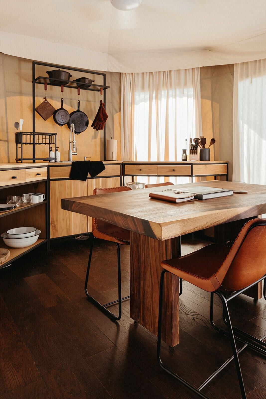 Una cocina moderna con armarios de madera, una gran mesa de madera y dos sillas de cuero.