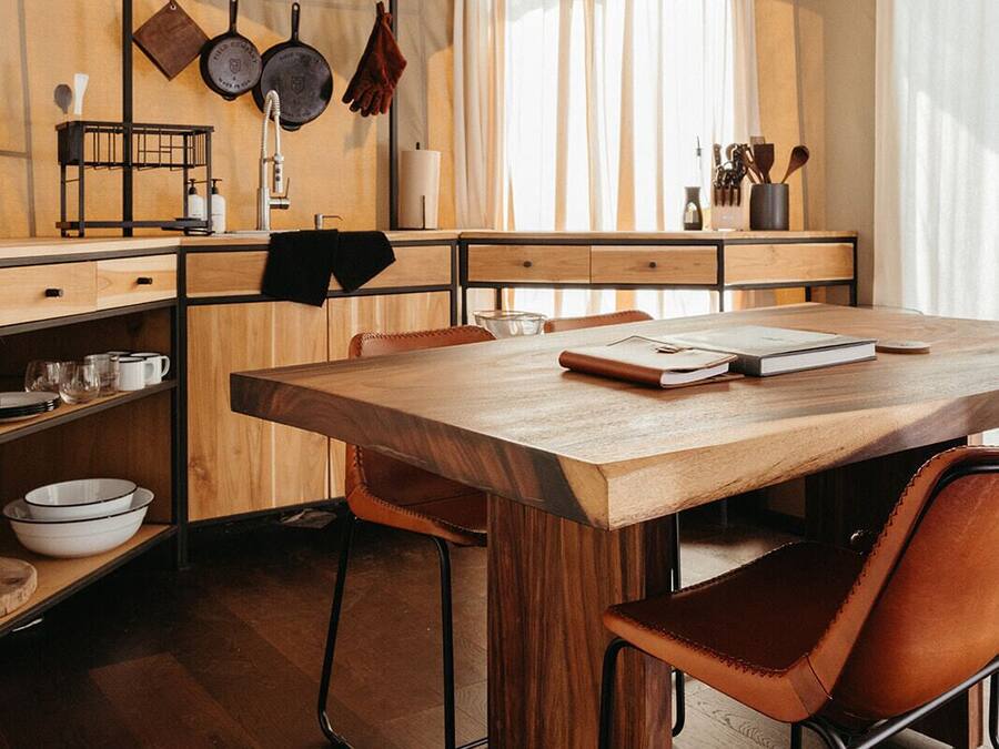 Una cocina moderna con armarios de madera, una gran mesa de madera y dos sillas de cuero.