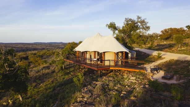 Alojamiento en carpa con terraza de madera y vistas del paisaje circundante.